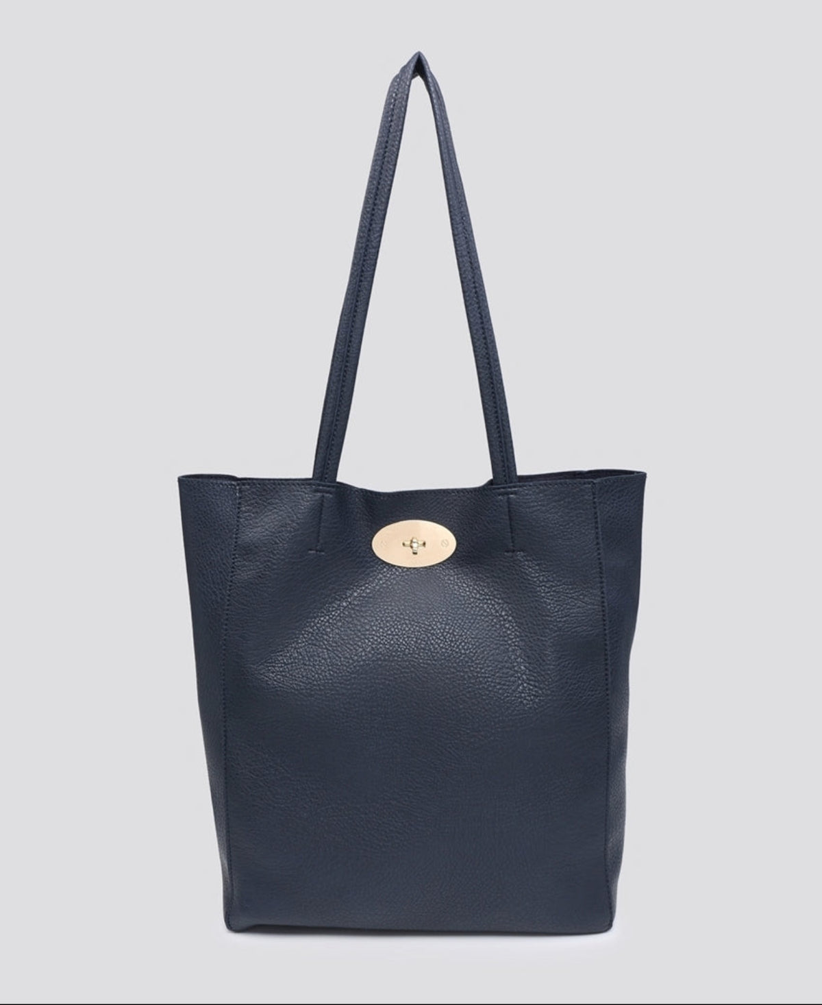 A navy blue pebbled leather tote bag with dual shoulder straps and a signature oval gold-tone button closure, shown against a solid light gray background.