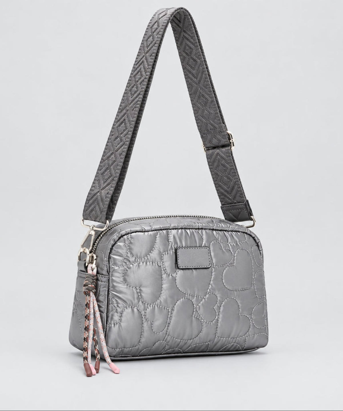 A silver quilted shoulder bag with a matching patterned strap