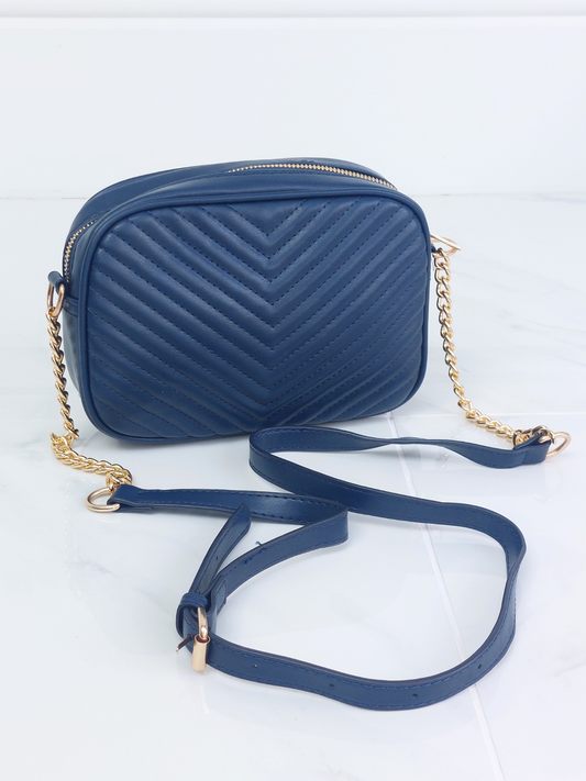 Navy blue crossbody bag with a gold chain strap on a white background