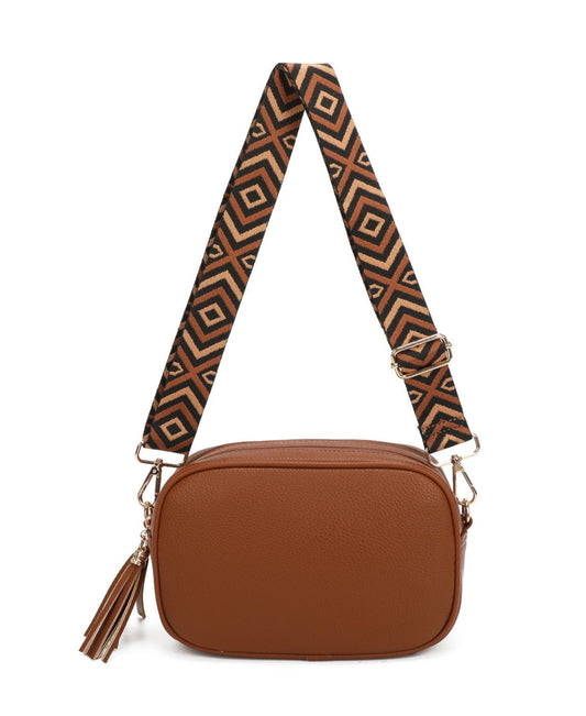 A brown faux-leather crossbody bag with a geometric patterned strap in brown, black, and beige, featuring a tassel charm on the side.