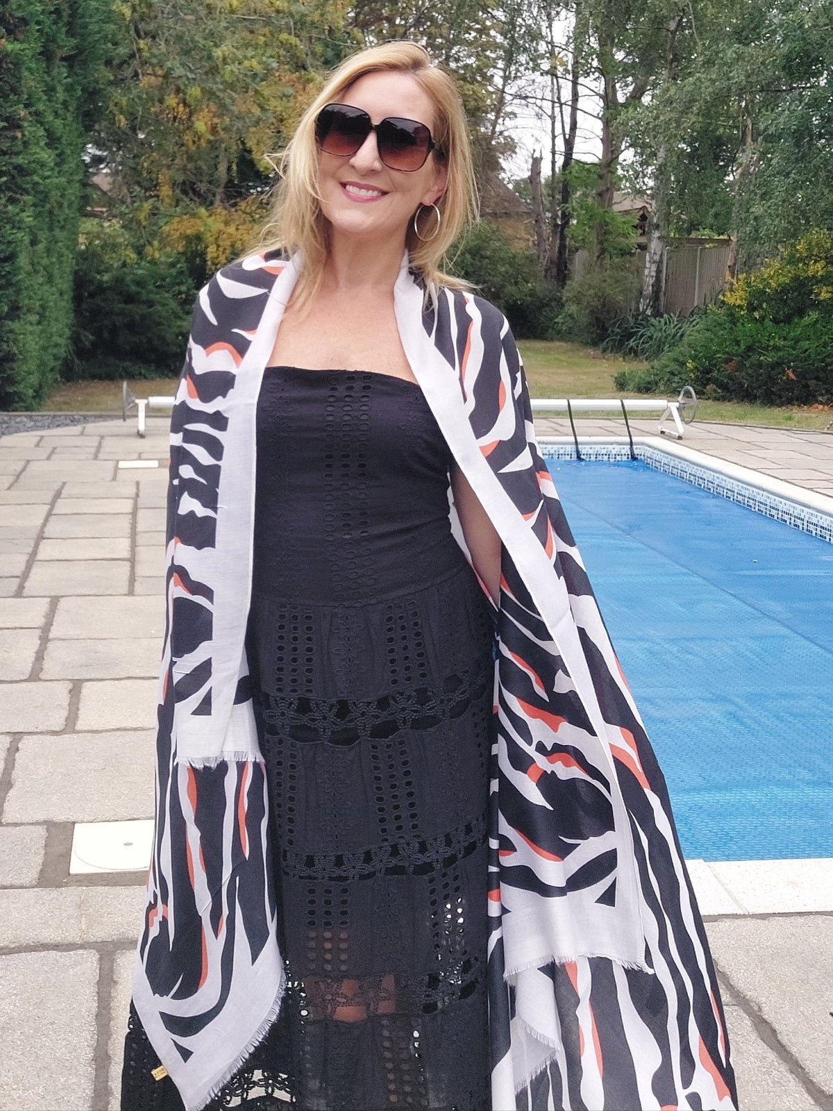 Woman wearing sunglasses and a patterned scarf by a poolside