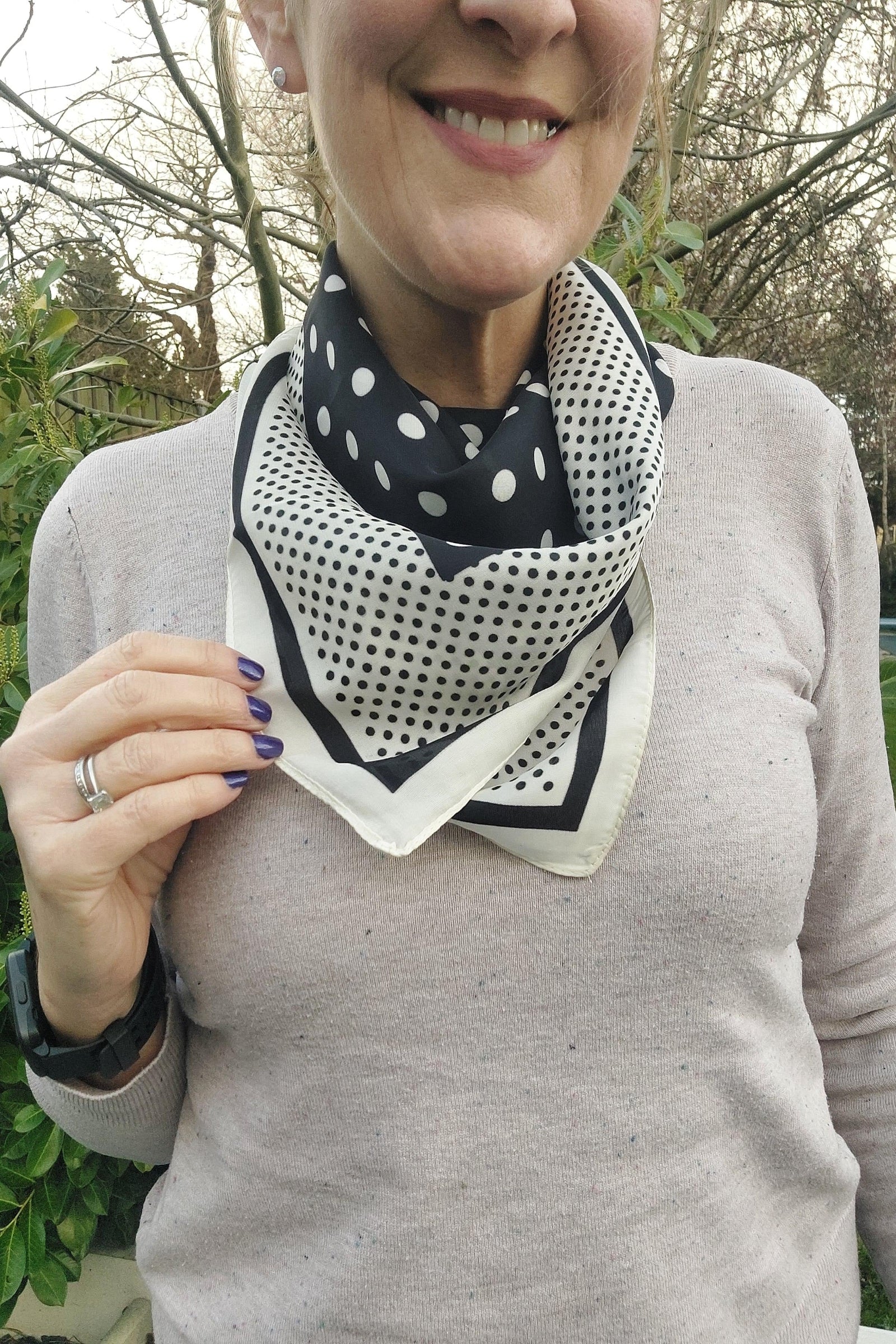 Person wearing a polka dot scarf outdoors with trees in the background