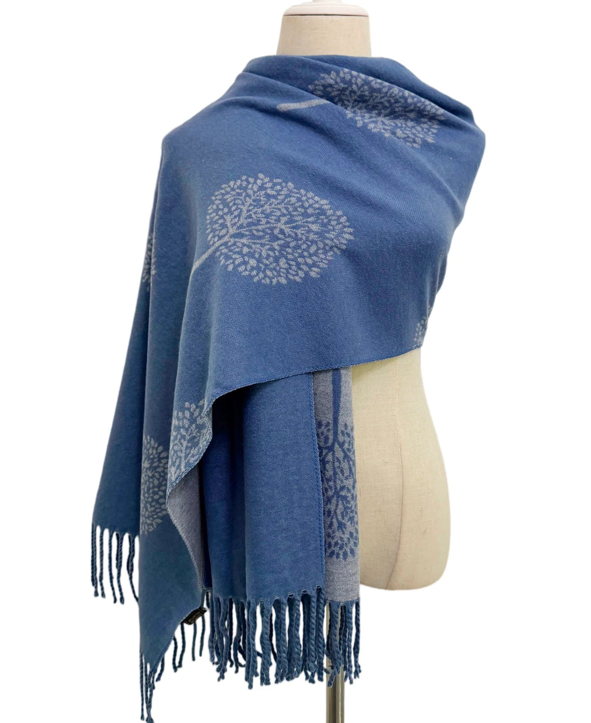 A blue pashmina shawl with light grey tree of life motifs and fringed edge.