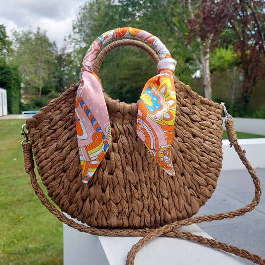 Woven handbag with colorful fabric accents on a grassy outdoor background