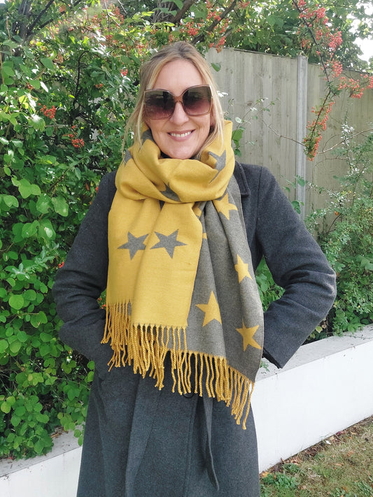 Person wearing a yellow scarf with star patterns in front of green foliage