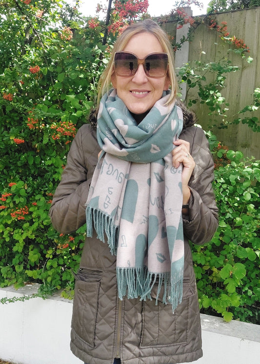 Woman wearing a patterned scarf and sunglasses outdoors with greenery in the background