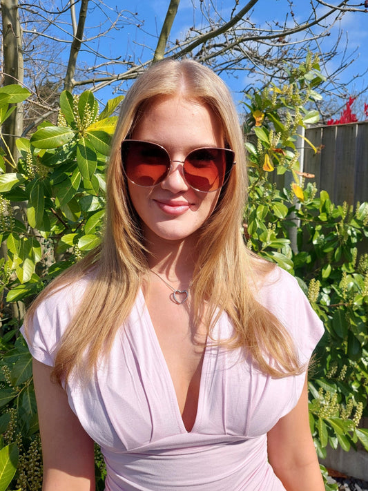Person wearing sunglasses and a light-colored top in a garden setting